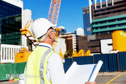 建筑工地的工程師建設(shè)者工程師建筑工人施工場(chǎng)景穿著帶藍(lán)圖的安全背心